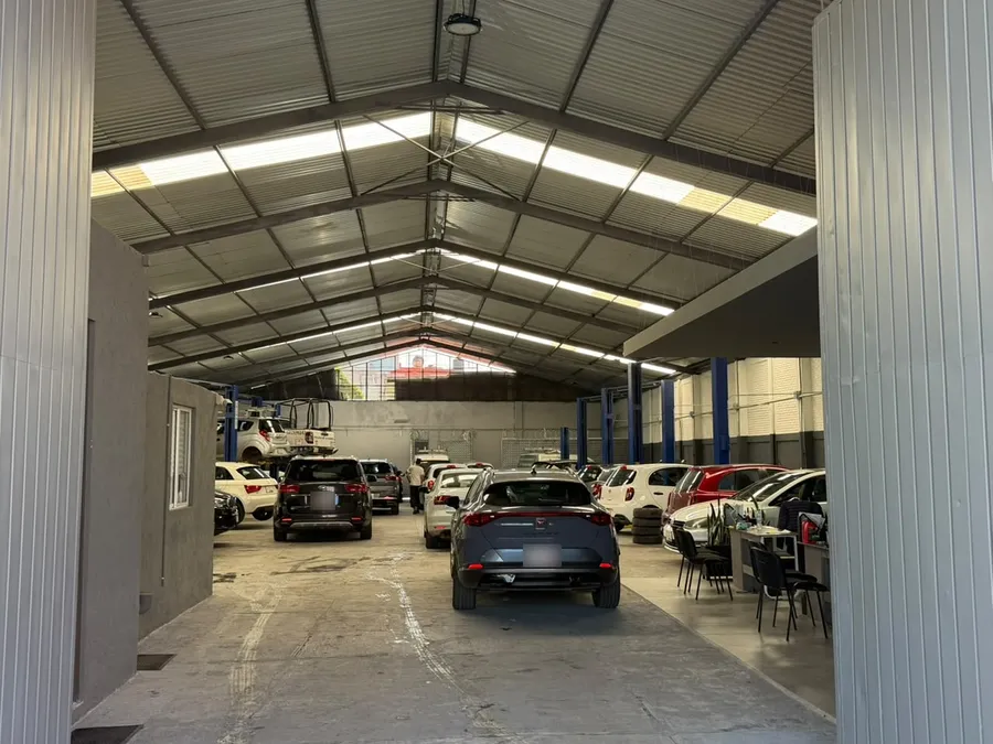El portón de la nave abierto hacia el patio techado, con unidades estacionadas al fondo.